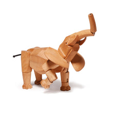 A beautifully crafted wooden elephant stands with it's trunk in the air. The elephant is made of large pieces of wood attached by a thick elastic string.