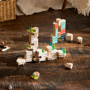 Wooden blocks are shown stacked in the shape of buildings. 