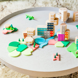 A circular table with wooden blocks stacked on top. The blocks look like a cityscape with stacked buildings and wide flat park spaces between.