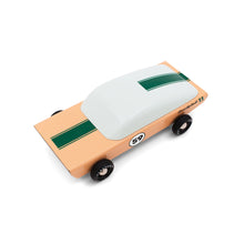 Wooden race car with a green racing strip over a sand colored body. The rear window of the car is long and curved, evoking a sense of speed and movement.