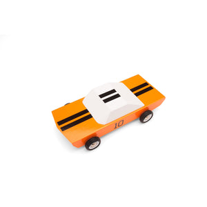 Top view of wooden race car toy. Car has an orange body, white cab, and black racing strips crossing down the middle of the car.