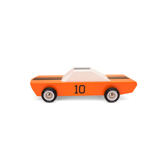 Side view of an orange wooden race car. The windows are painted white, and black stripes cross the hood, roof, and trunk.