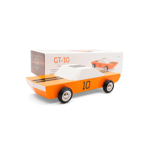 Wooden race car toy. Orange, white, and black car sit in front of product packaging.