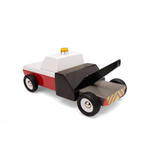 Rear view of wooden tow truck. The truck is red, white, and black with yellow caution stripes on the rear end. An orange safety light is visible on the roof.