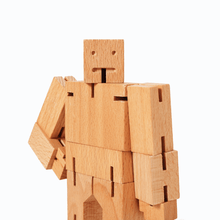 A close up of a wooden robot. The head and upper body are visible, each made of rectangular pieces of wood joined by elastic string.