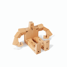 A wooden robot toy sits on the ground with legs straight out and hands resting on the ground.
