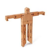 A wooden robot toy stands on tip-toe with it's arms out horizontally. The robot is made from a warm colored unpainted wood.