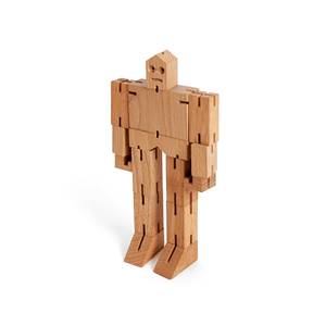 A wooden robot toy stands at attention, made from blocks of unfinished wood.
